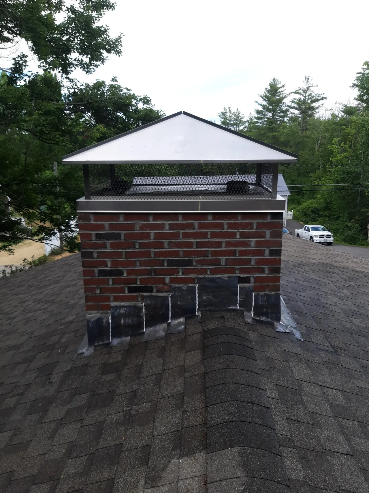 The chimney flashing is the metalic (lead) material in between the brick and the roofing shingles.